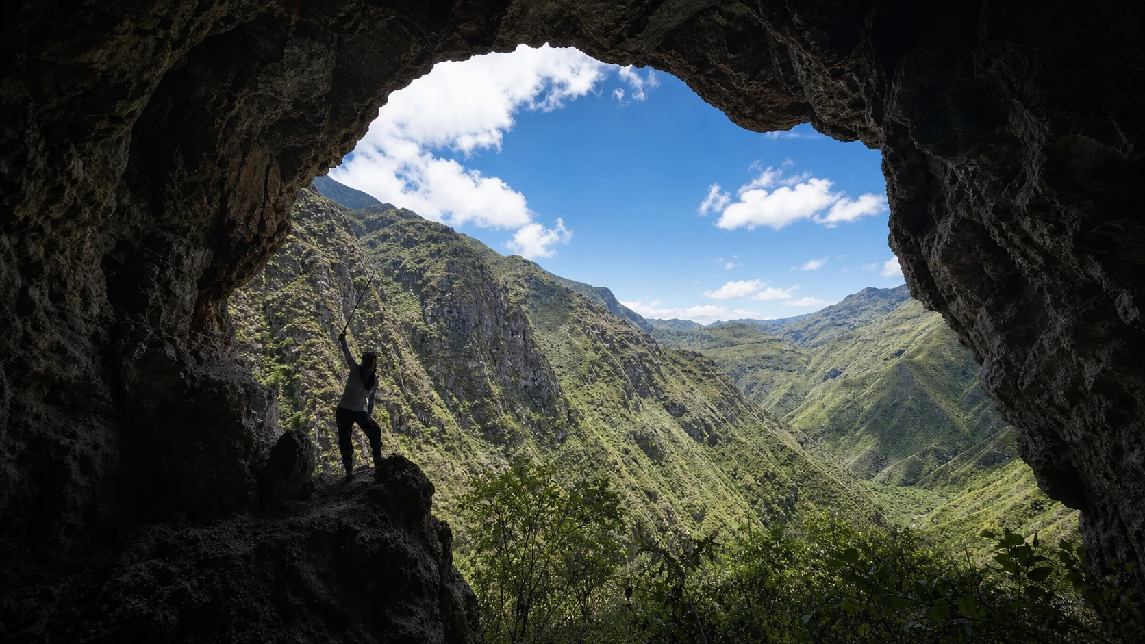 A lone hiker framed by a cave opening above the Cañar Andes